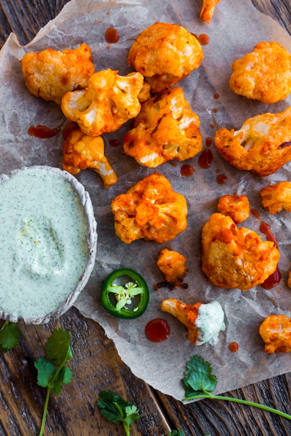 Parchment paper topped with buffalo cauliflower with slices of jalapeño and cilantro