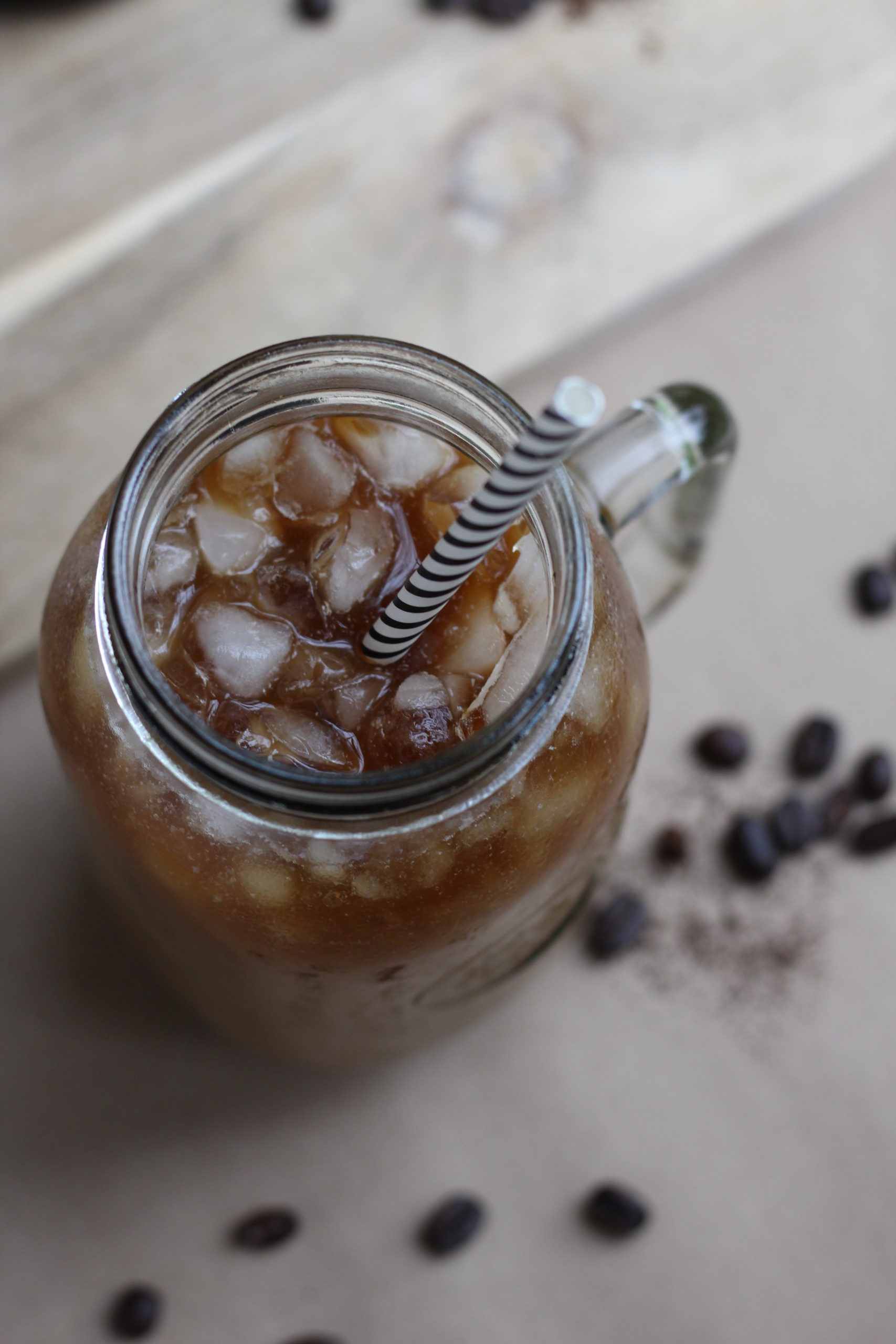 A glass jar with iced coffee and a striped straw