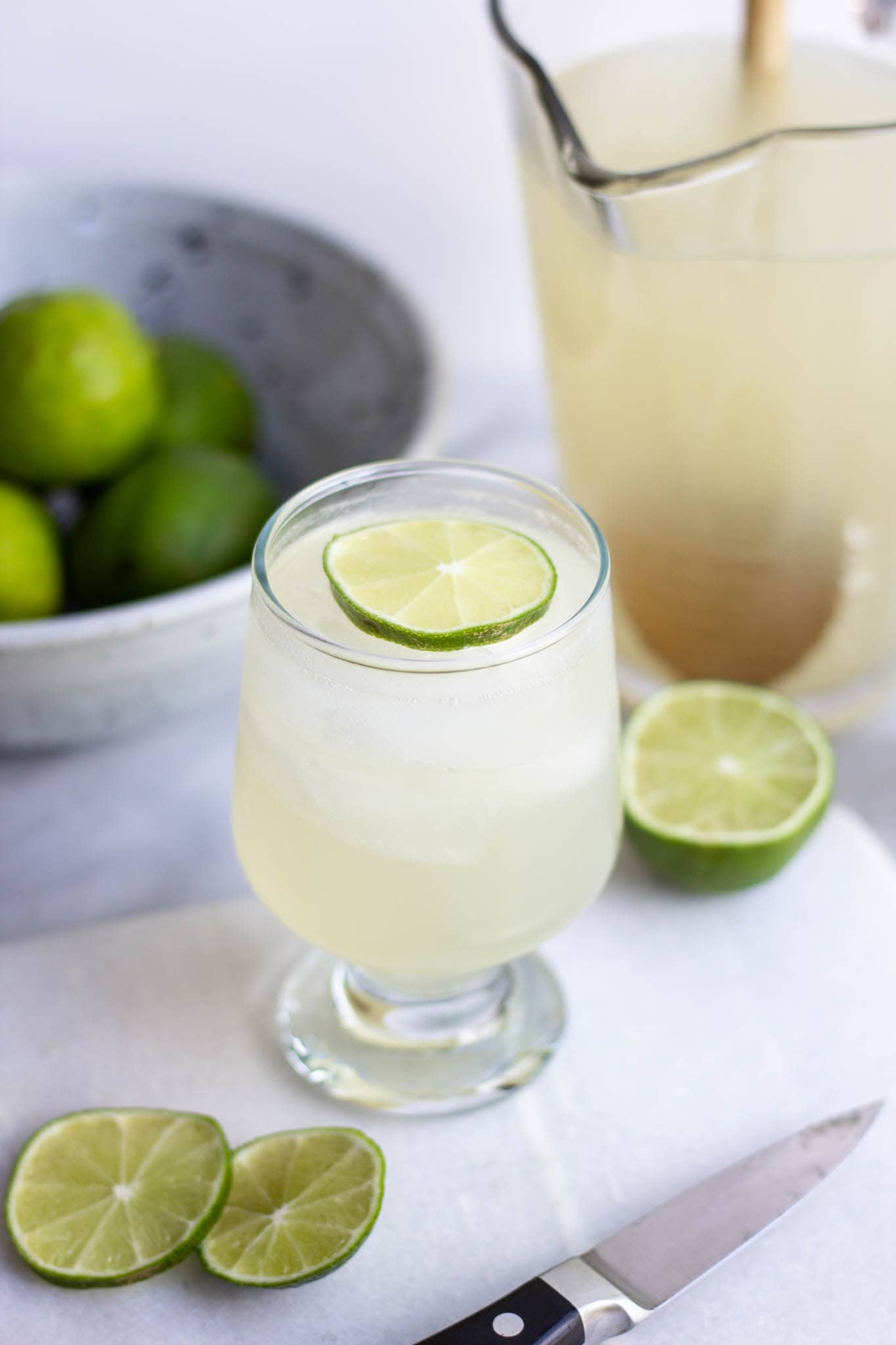 A glass of coconut water limeade with fresh sliced lime in the glass.