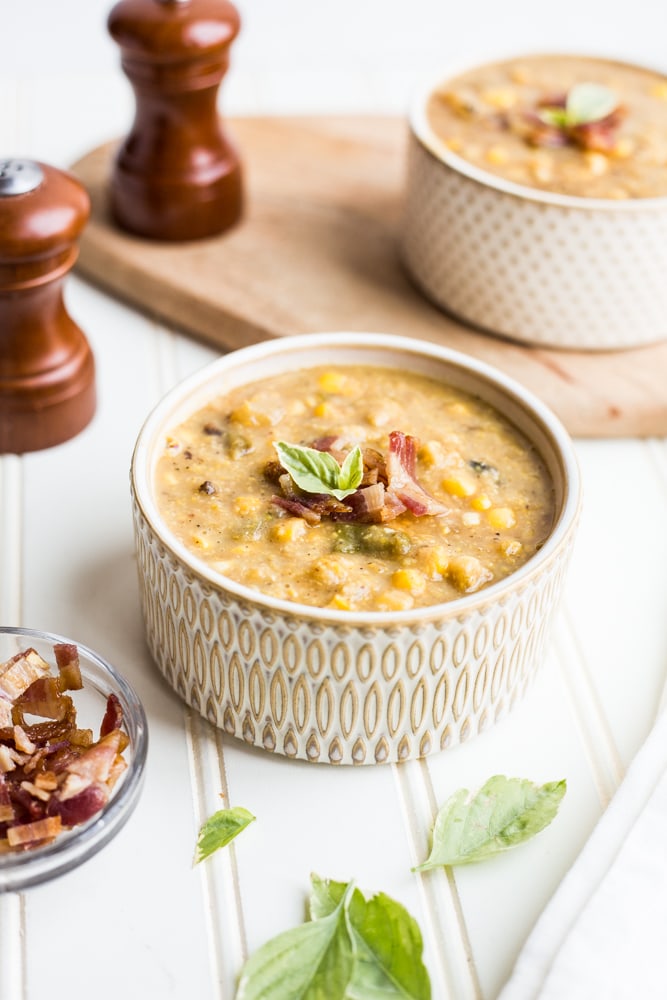 A bowl of summer corn and poblano chowder topped with bacon and basil