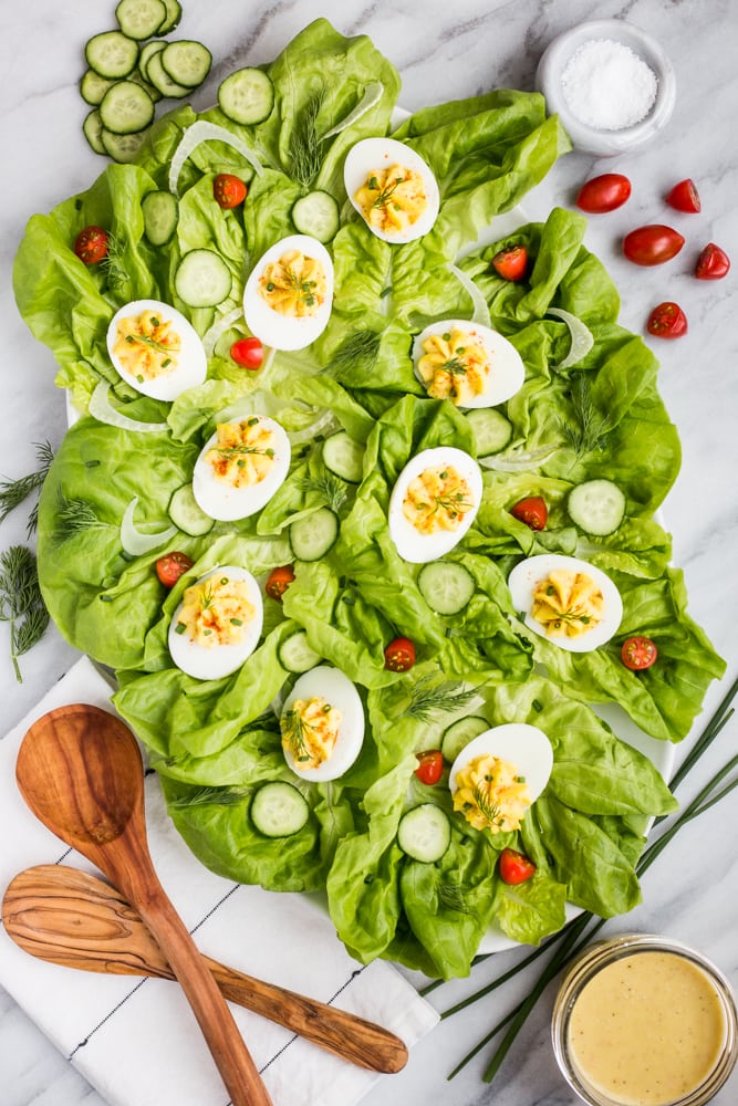 A plate of lettuce topped with tomatoes, cucumber, and deviled eggs