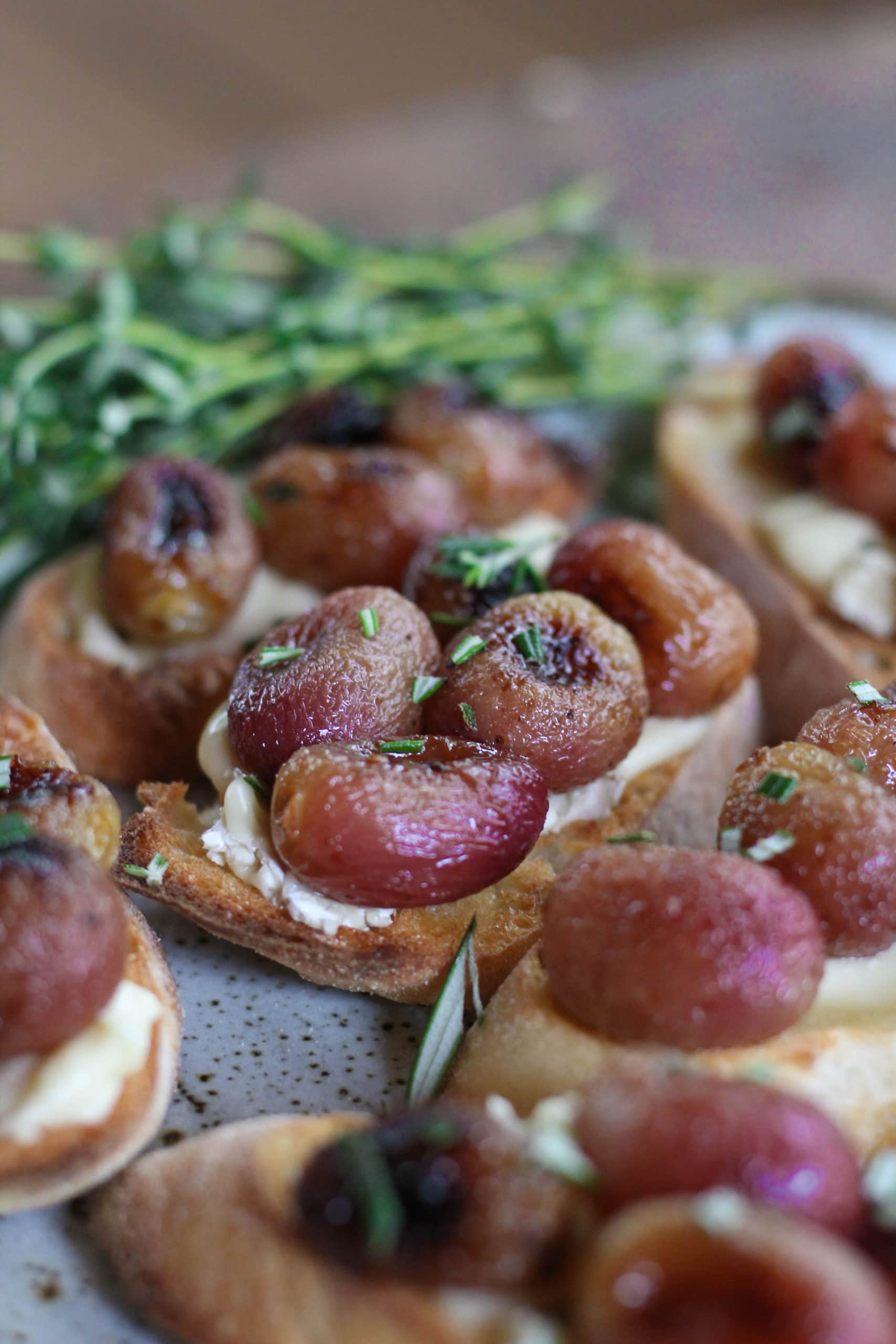 A plate filled with roasted grape and brie crostini