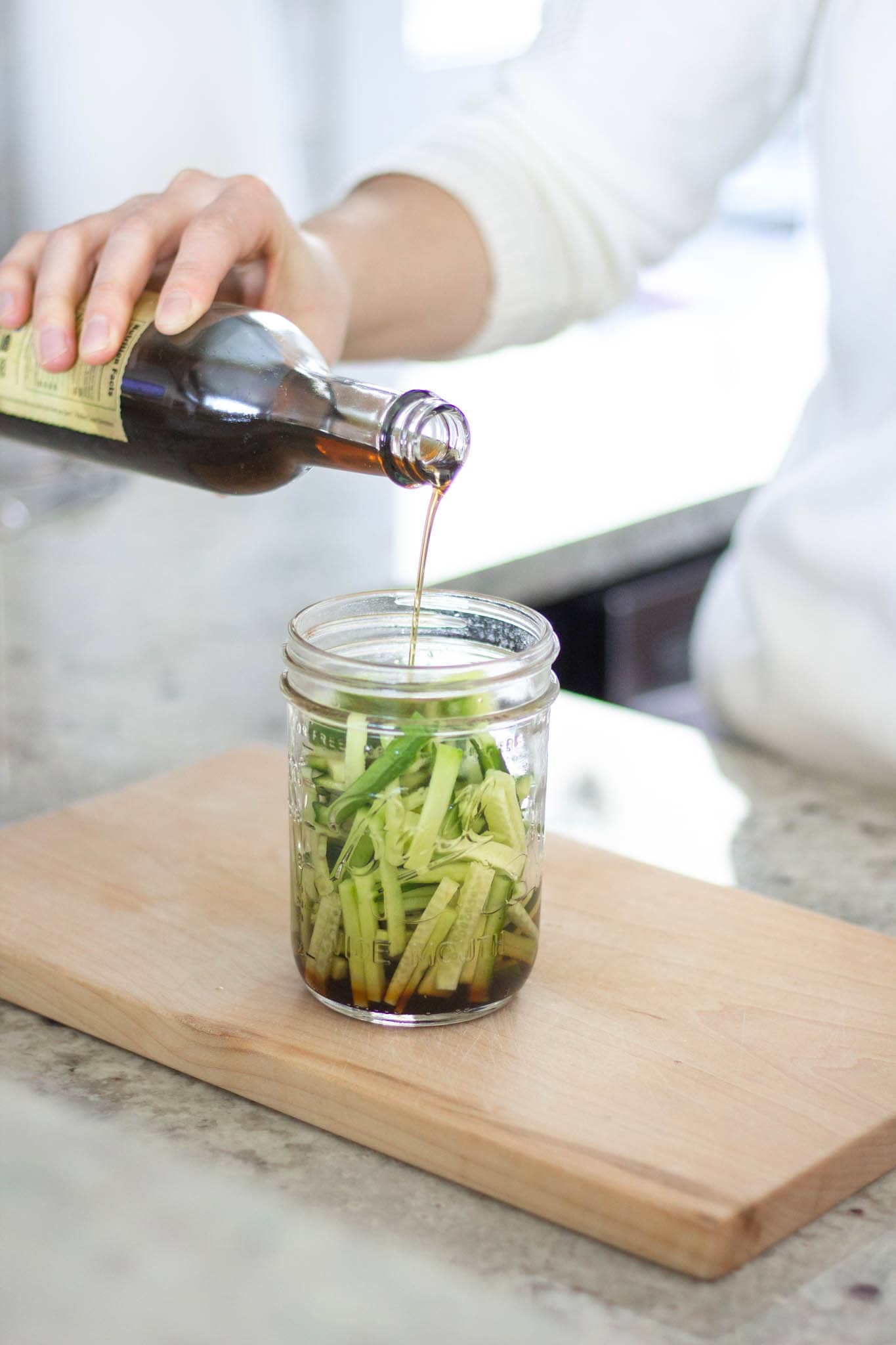 A jar of cucumbers being poured with sesame oil