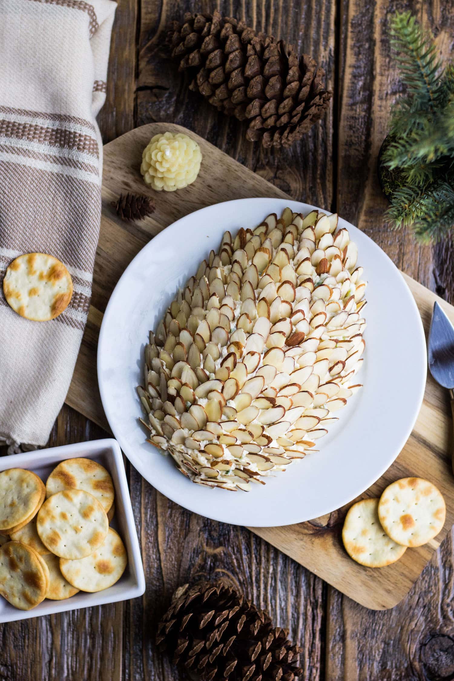 A pineapple cheese ball covered in almonds looking like a pinecone