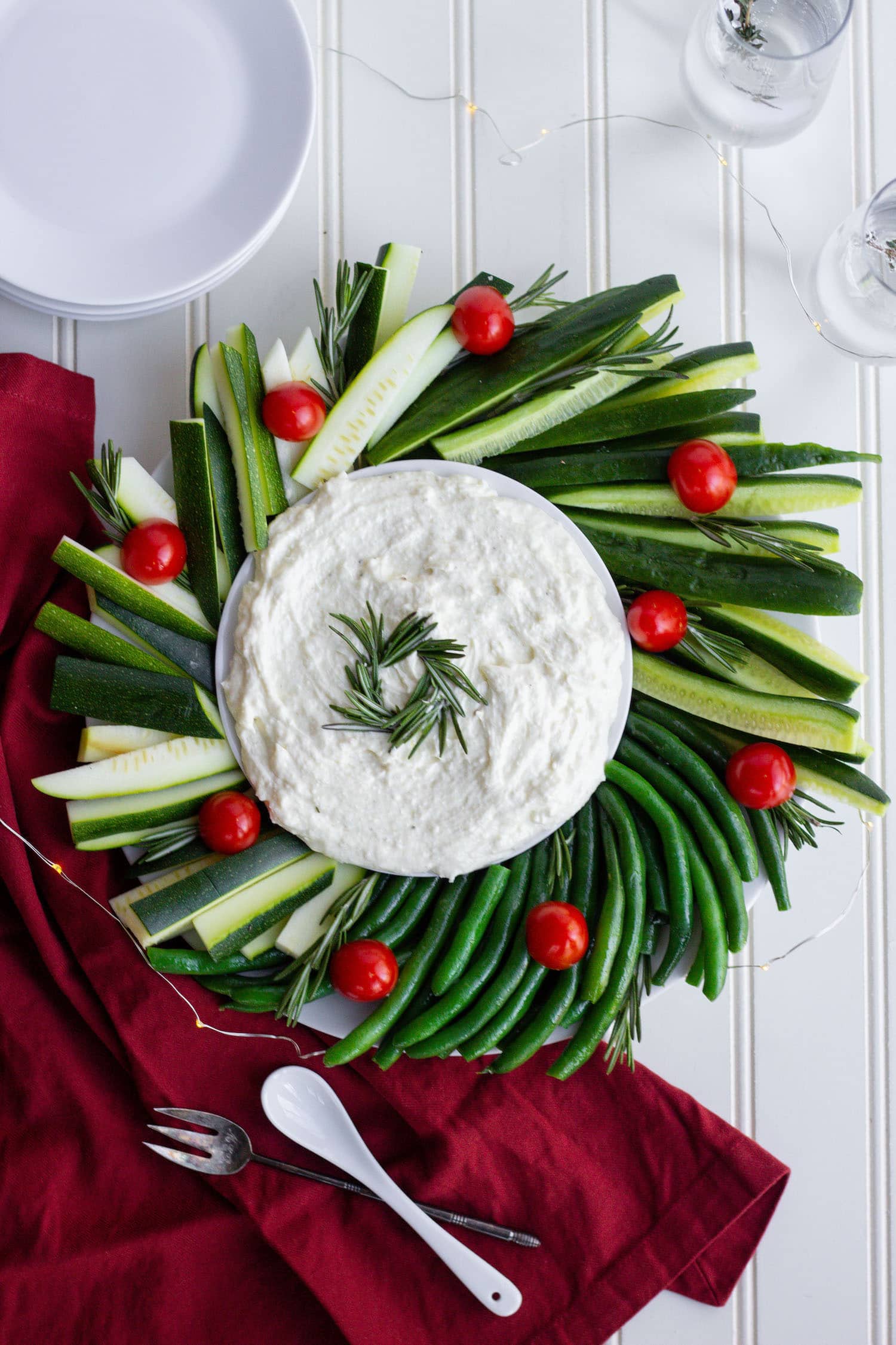 A platter of red and green vegetables shaped as a wreath surrounding whipped feta
