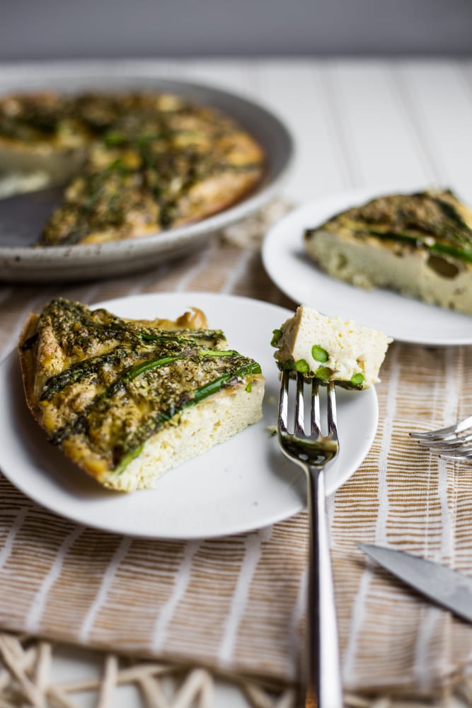 Piece of asparagus and feta frittata on a plate with a fork
