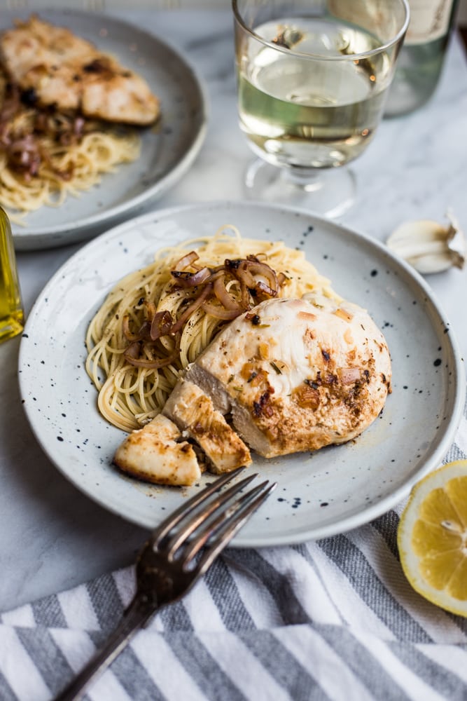 A plate of pasta topped with French lemon chicken with shallots