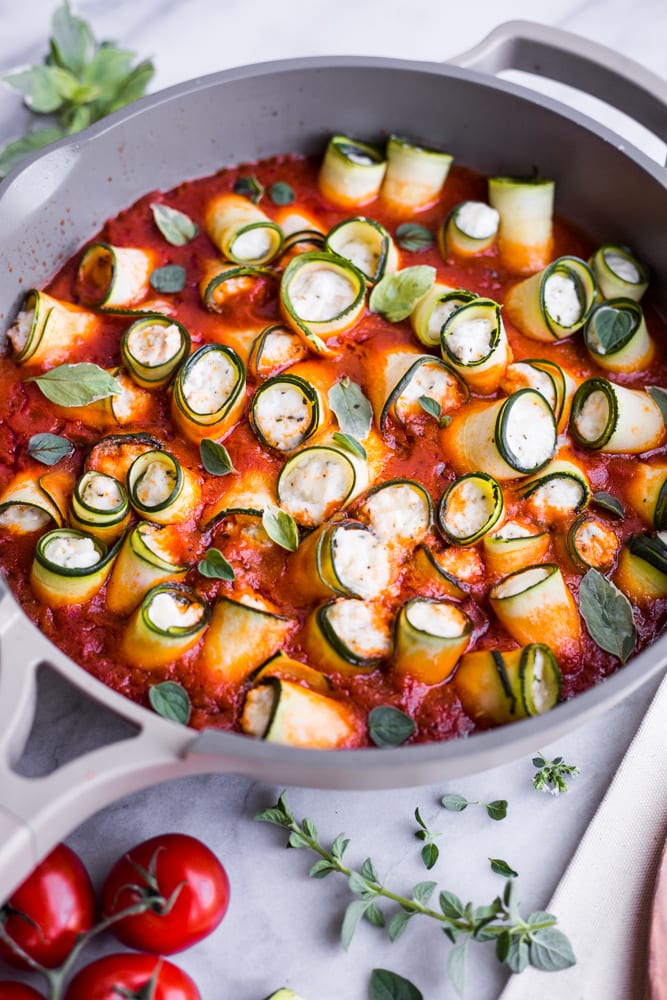 A pan of herbed zucchini roll ups with marinara