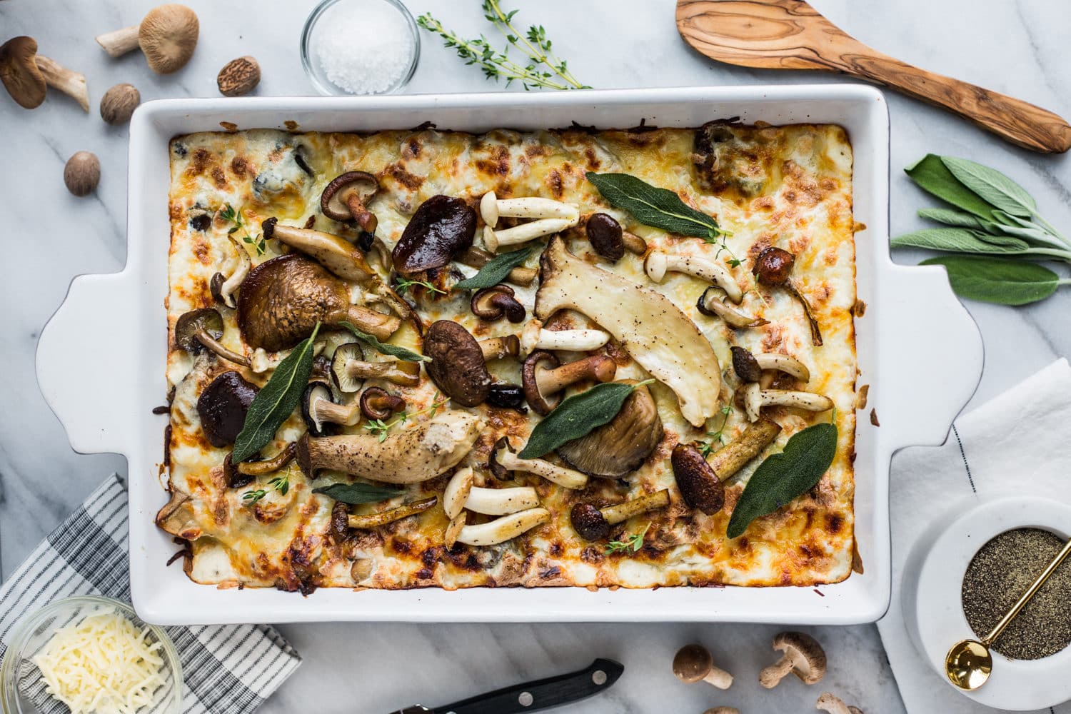 A pan of lasagna topped with roasted mushrooms and sage