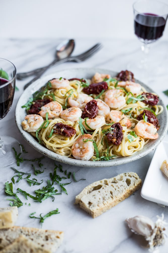 A plate of pasta with sun-dried tomatoes, shrimp, and basil