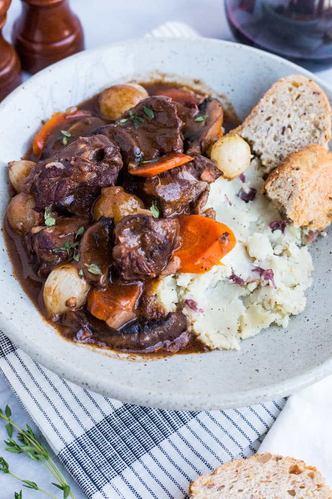 A plate of beef bourguignon served over mashed potatoes