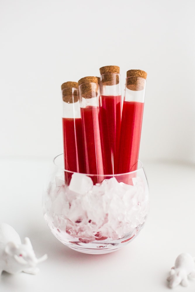 A cup holding vials with red liquid in them