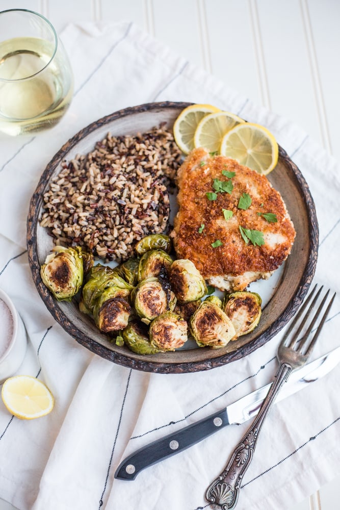 A dinner pate with pork schnitzel, roasted Brussels sprouts, and quinoa pilaf