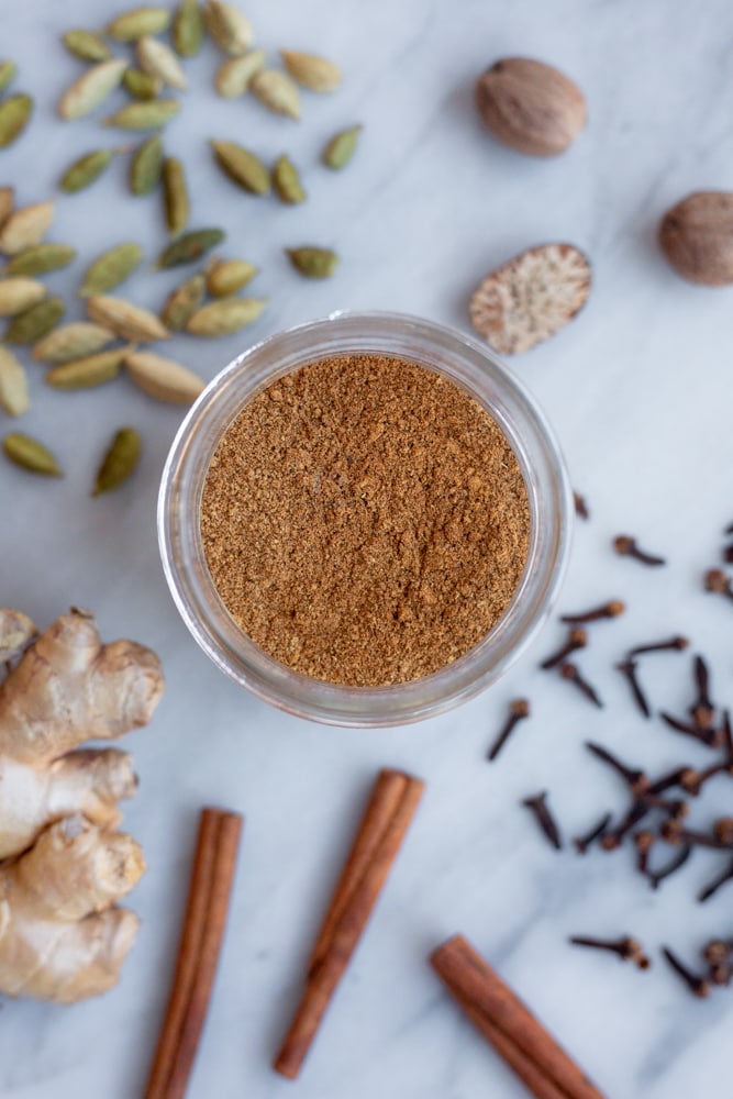 A jar of homemade chai spice mix surrounded by spices