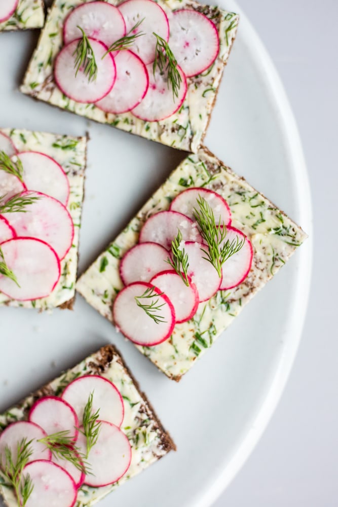 A plate of radish canapés with herbed butter and topped with fresh dill