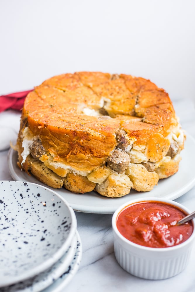 A savory cheesy meatball pull apart bread with a bowl of marinara near it