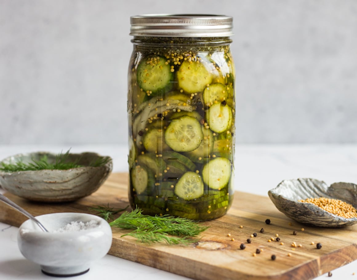 A jar of quick pickles on a wooden cutting board