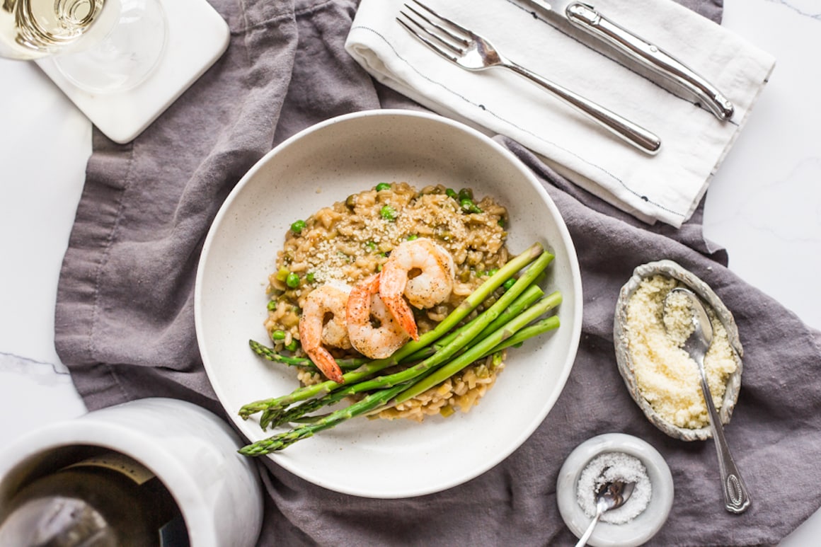 A bowl filled with risotto and topped with asparagus and shrimp
