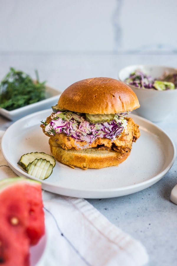 A fried chicken sandwich topped with dill pickle slaw and pickles