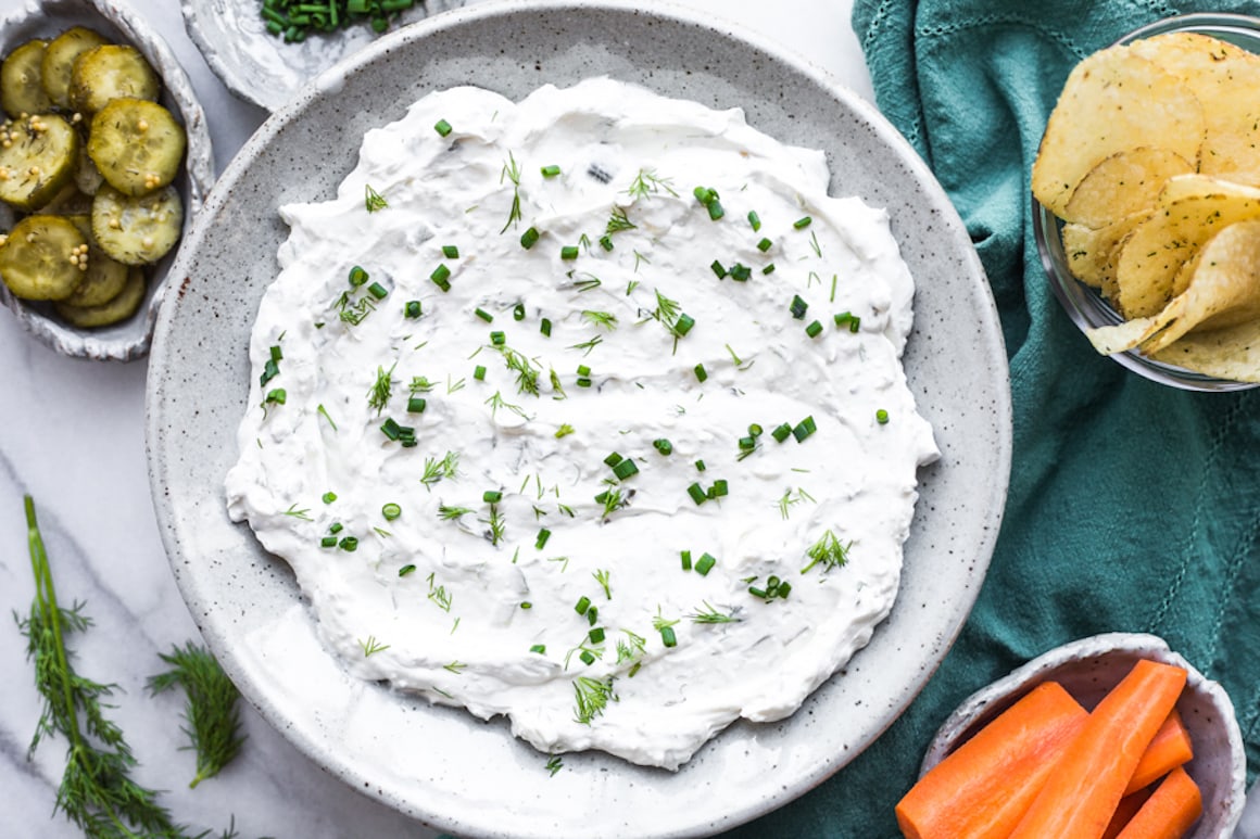 A bowl of dill pickle dip topped with dill and chives
