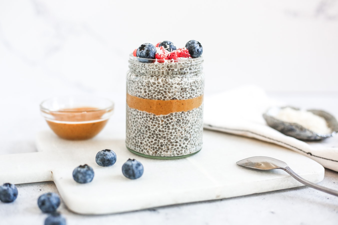 A jar layered with chia pudding and peanut butter, topped with berries