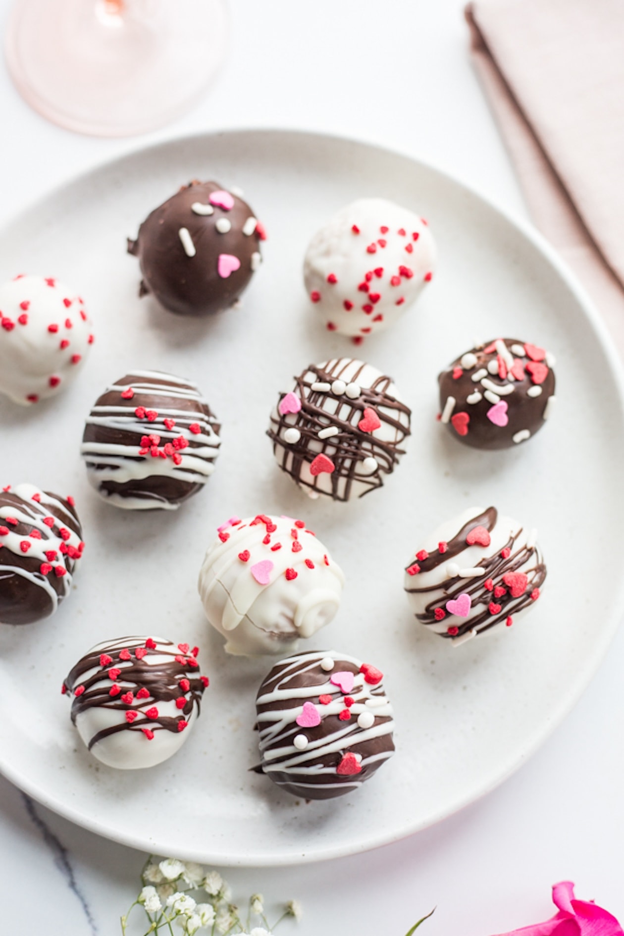 A plate of chocolate covered truffles covered with red and pink Valentine's Day sprinkles