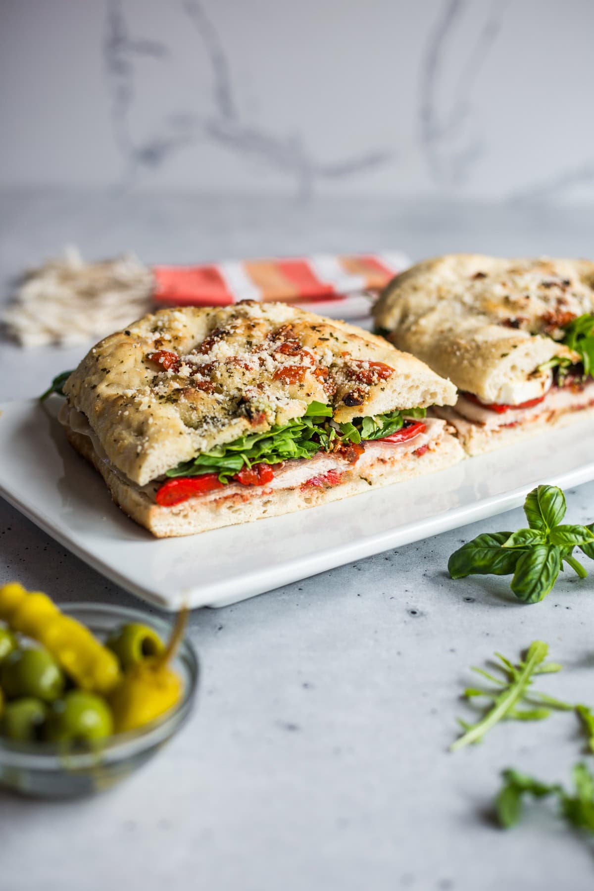 A focaccia sandwich with roasted red peppers, arugula, turkey, prosciutto, and mozzarella