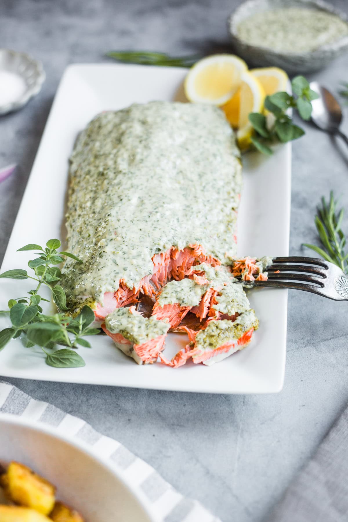 A platter of flaked salmon topped with green goddess sauce