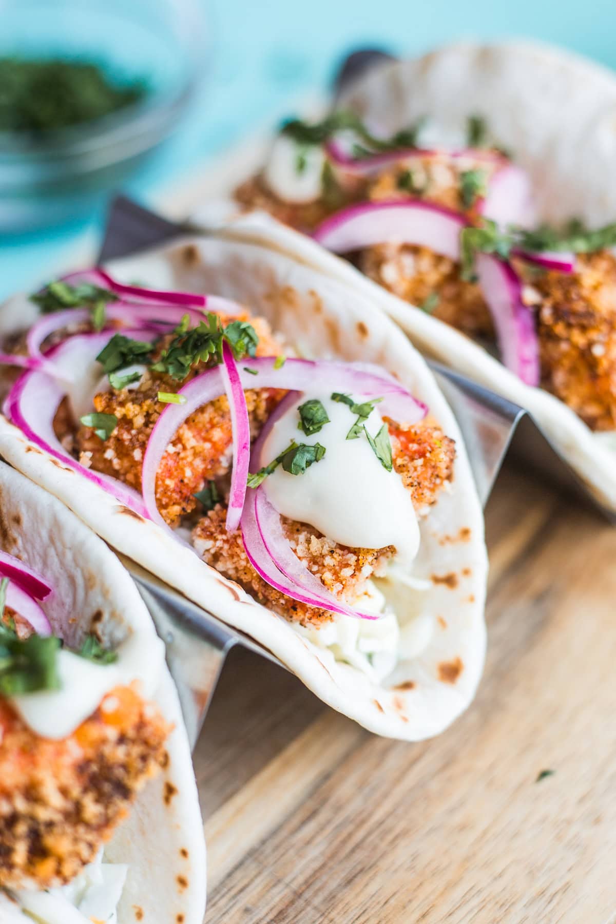 Tacos filled with cilantro coleslaw, crispy salmon bites, pickled red onion, and topped with chopped cilantro