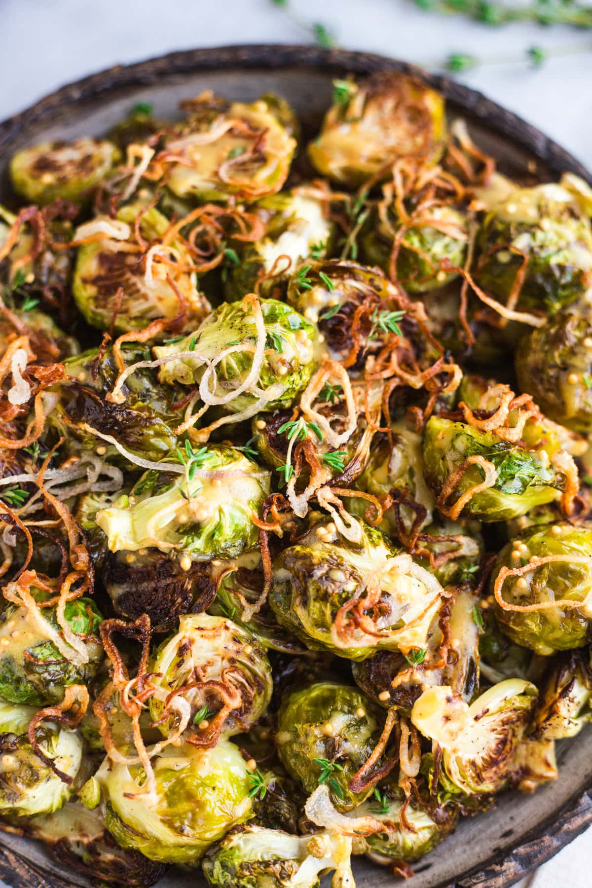 A platter of roasted Brussels sprouts topped with crispy shallots and a mustard vinaigrette