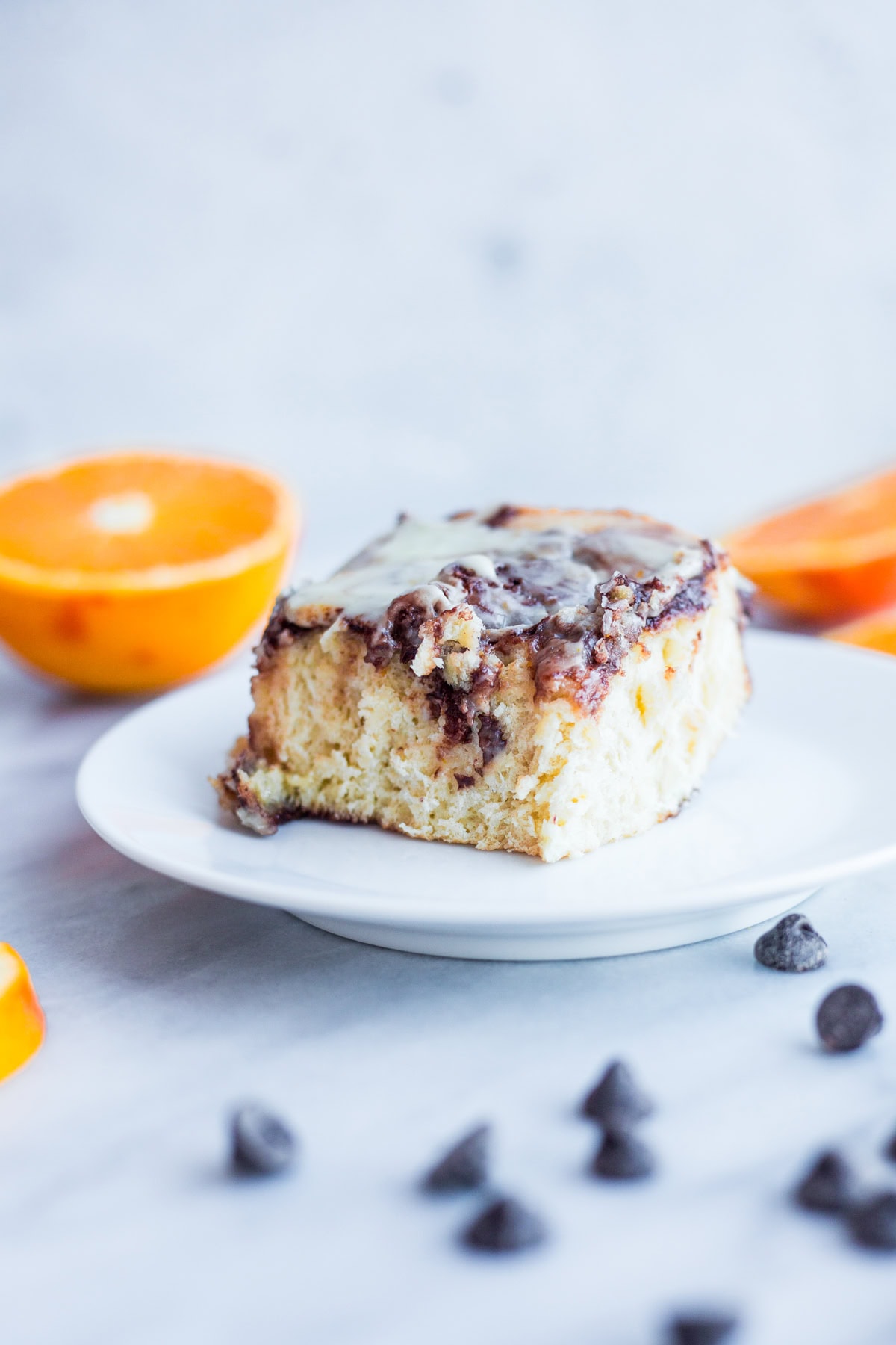 A chocolate and orange sweet bun on a white plate