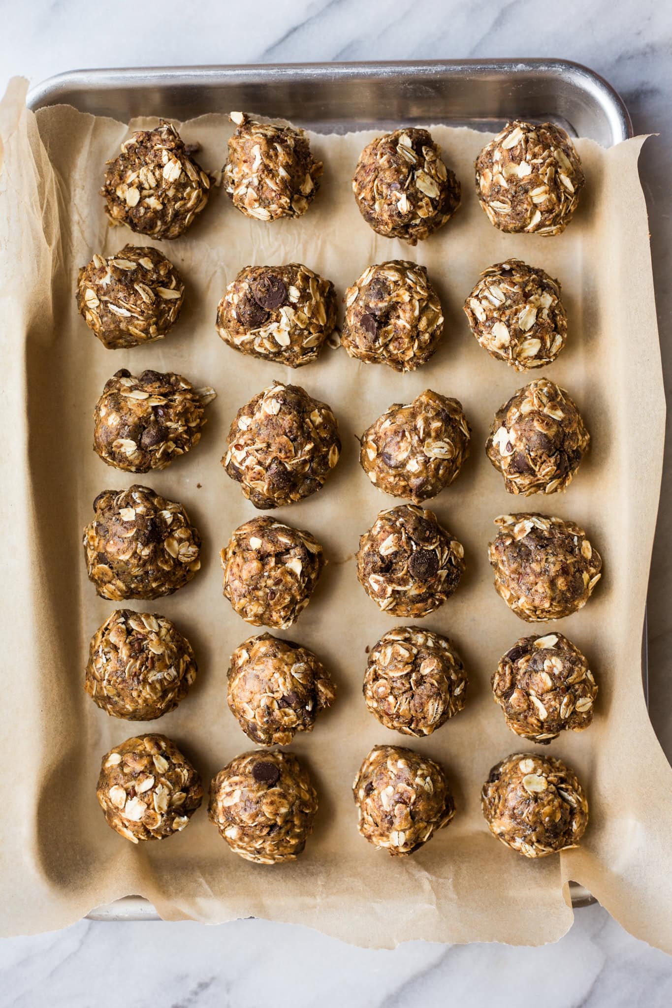 Oatmeal and chocolate chip lactation bites lined up on a baking sheet