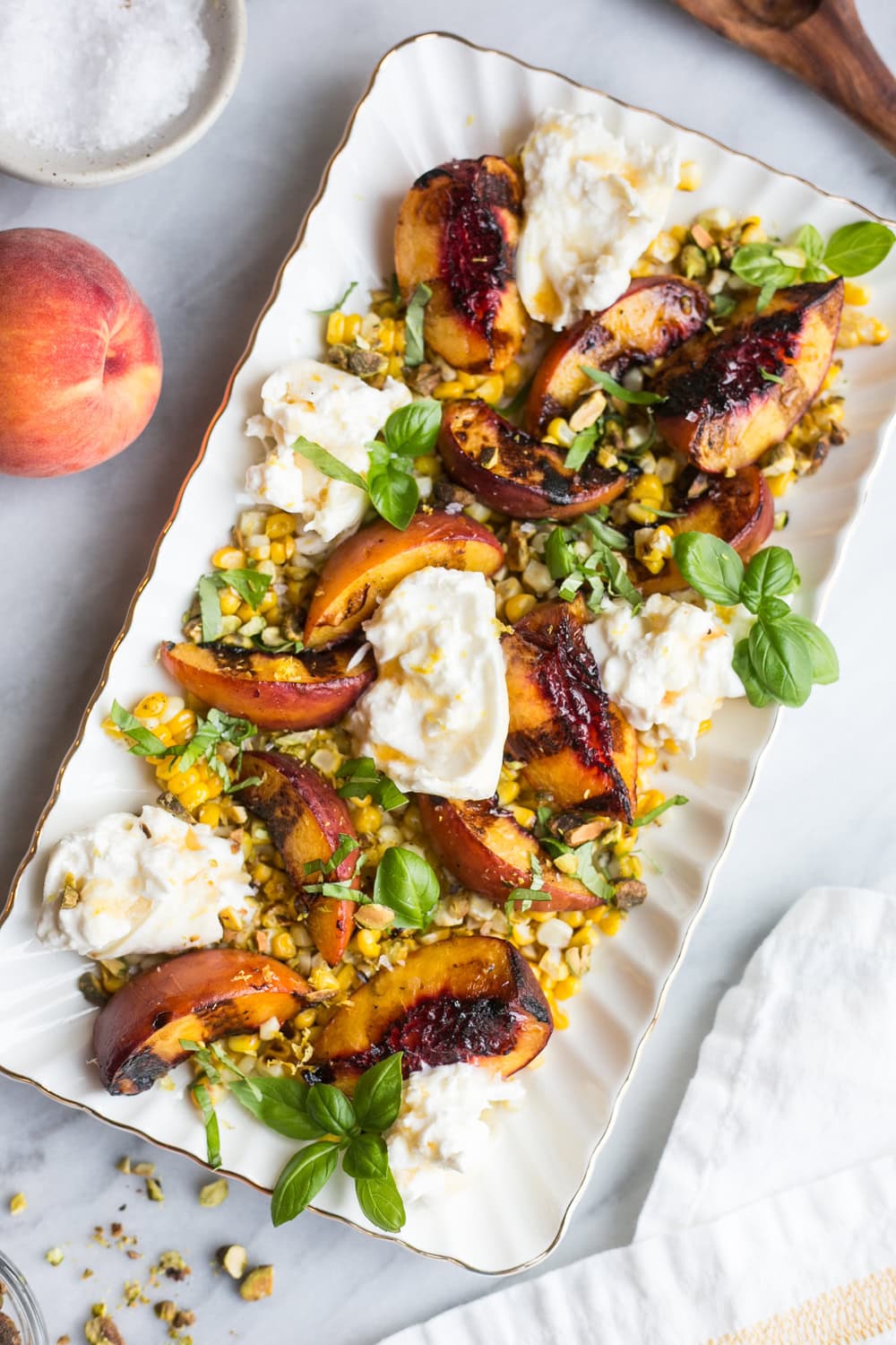 Grilled peach burrata salad with charred corn, pistachios, basil, and hot honey