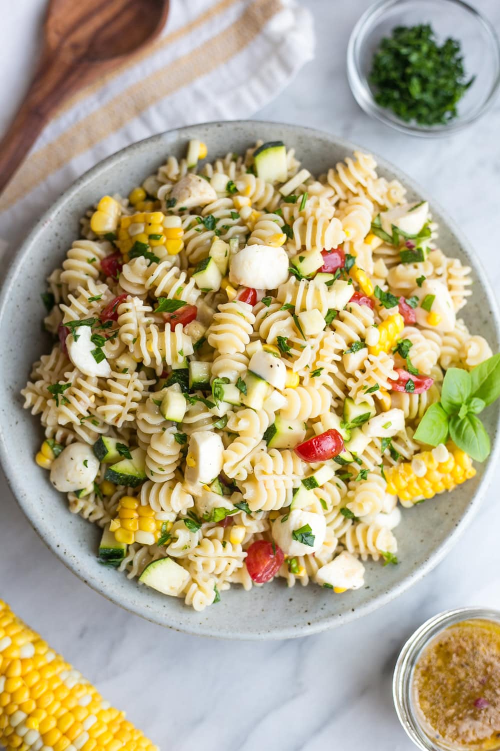 Summer pasta salad with corn, zucchini, cherry tomatoes, mozzarella, basil and parsley